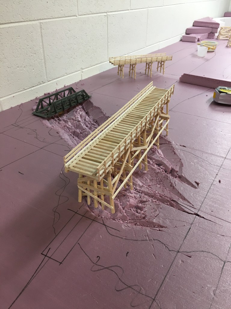 A scratch-built balsa wood bridge stands, waiting for a place to rest.