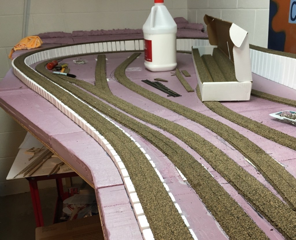 Pink extruded foam is the baseboard. Styrofoam risers lift the track. Cork roadbed is the base under the track.