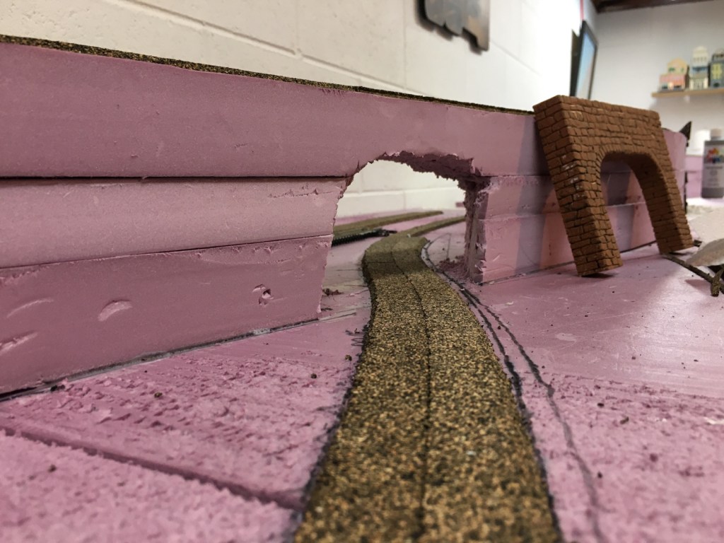 Cork roadbed through tunnel, rough edges show need for sanding.