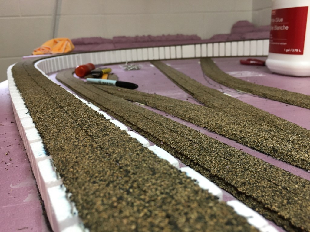 After cork roadbed is glued in place, the beveled edge should be sanded smooth.