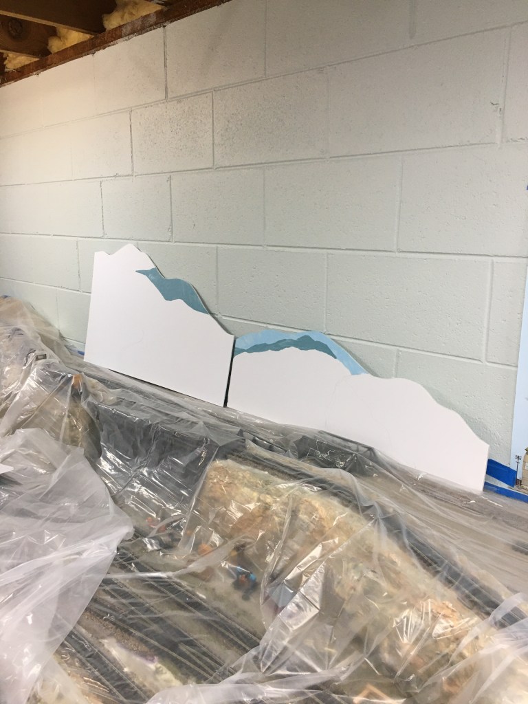 Backdrop painting begins. The top of the foam board was cut to indicate mountain range.