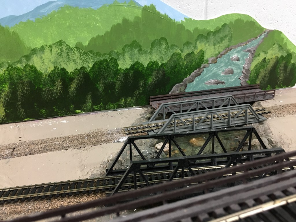 Four bridges crossing the Maple Valley River in front of painted backdrops.