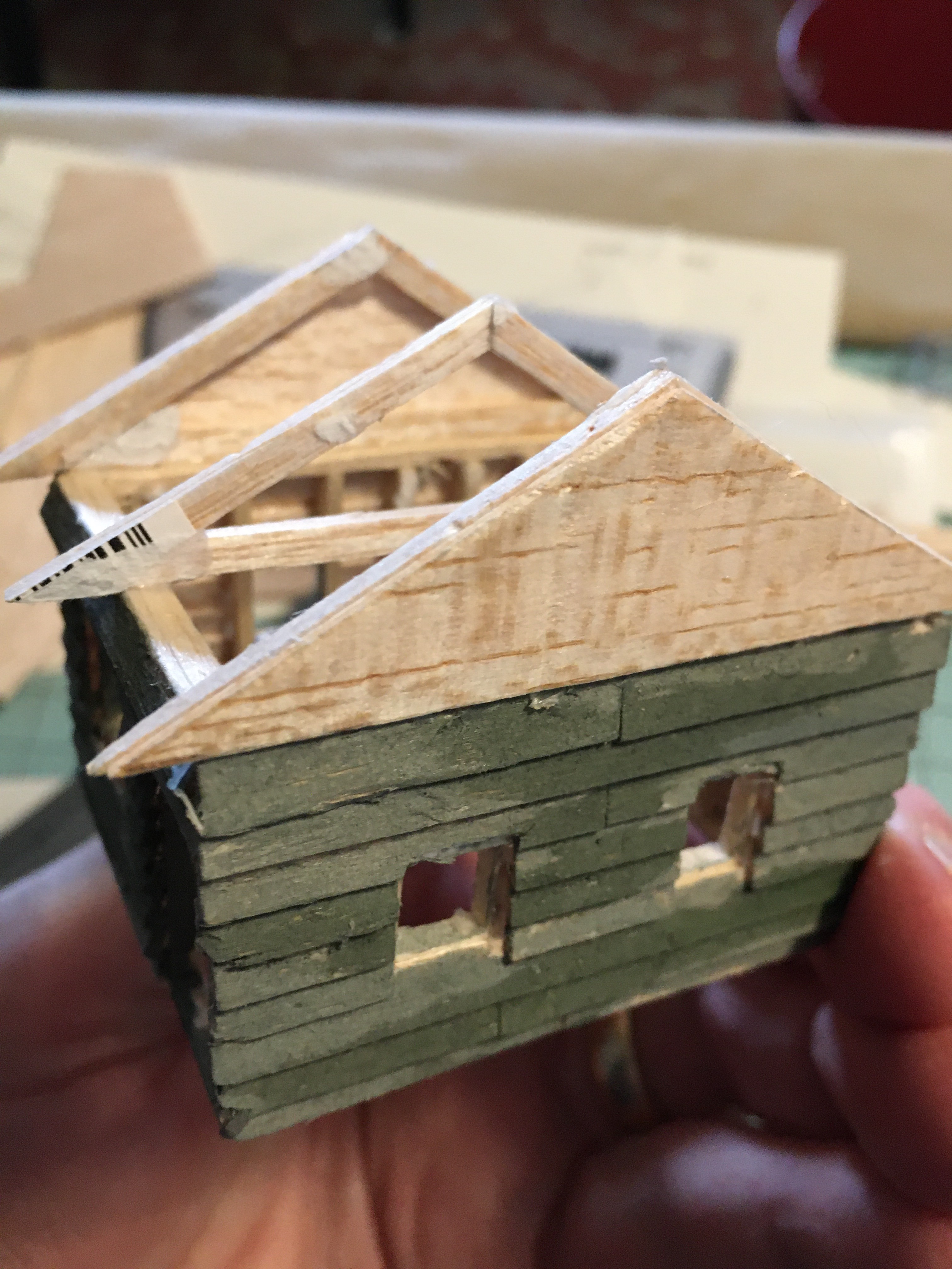 Very small cabin showing two windows and roof trusses.