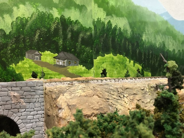 Acrylic painting with cabin and shed. Rock formations and elevated track.