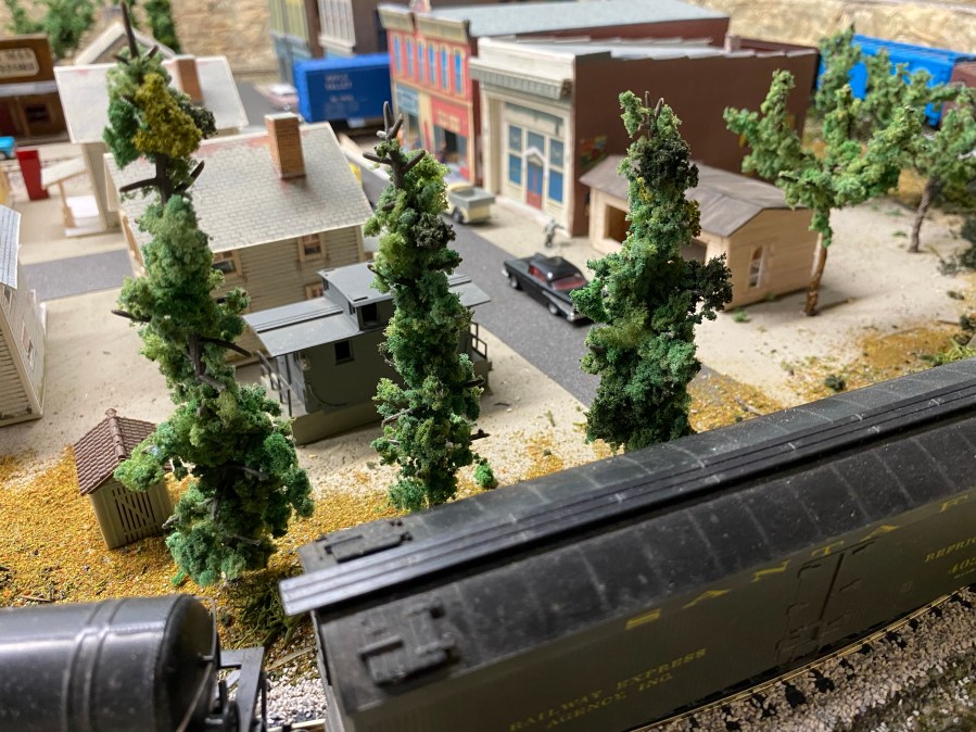 Train cars, trees, buildings, cars, streets