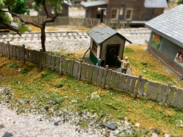 Finished balsa picket fence leaning by a tree.