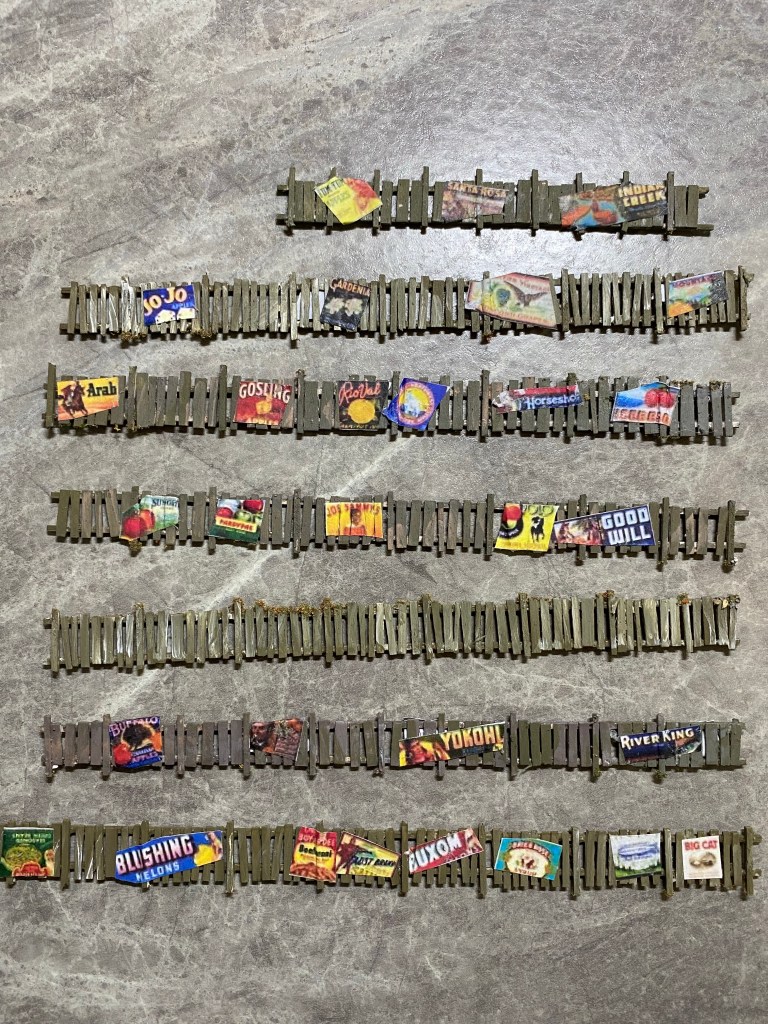 Painted picket fences with posters glued on them.