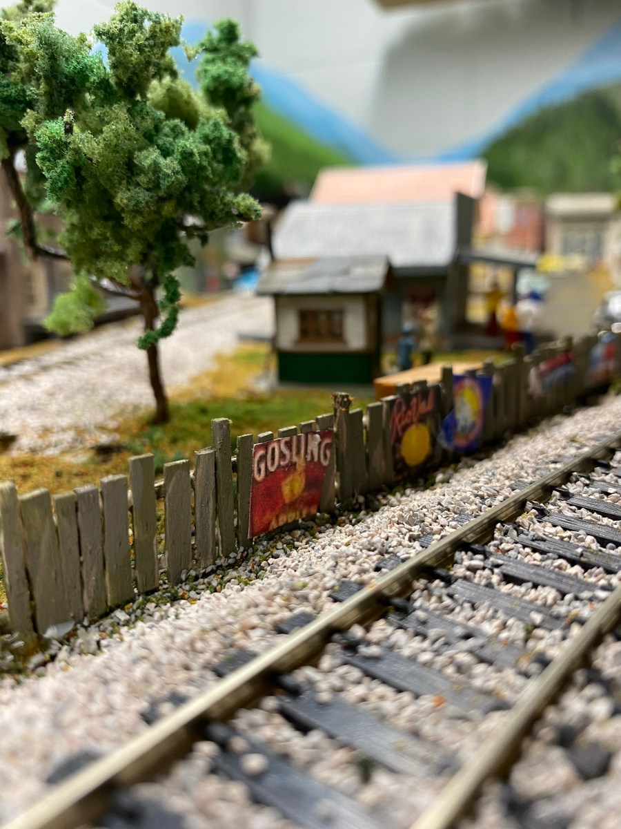 Train track, fence, trees, buildings, grass