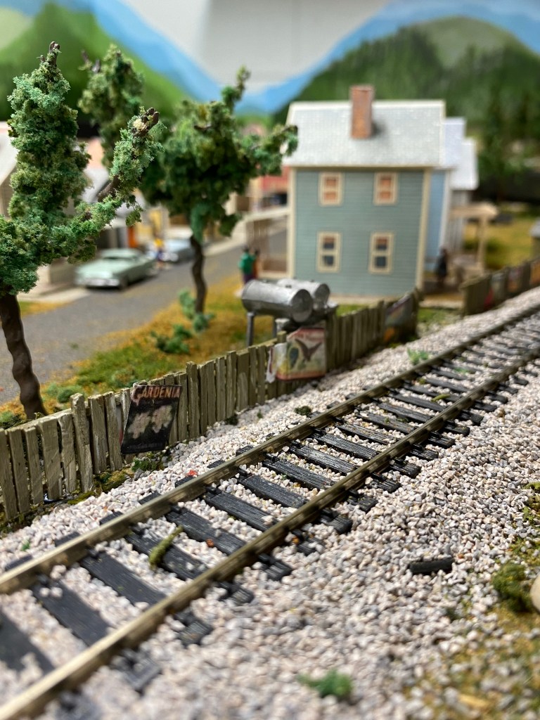 Green picket fence with poster along trackside.