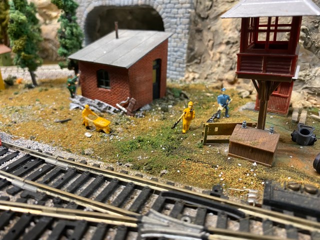Small shed, workers, control tower near tracks.