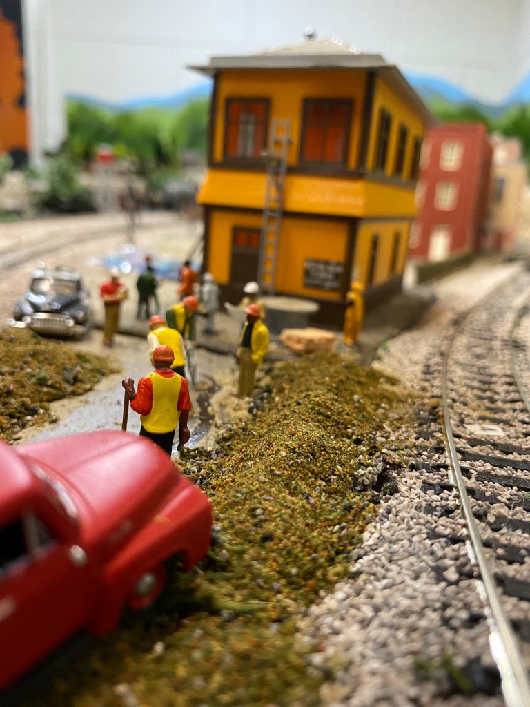 A red truck sits near piles of dirt where men are working.