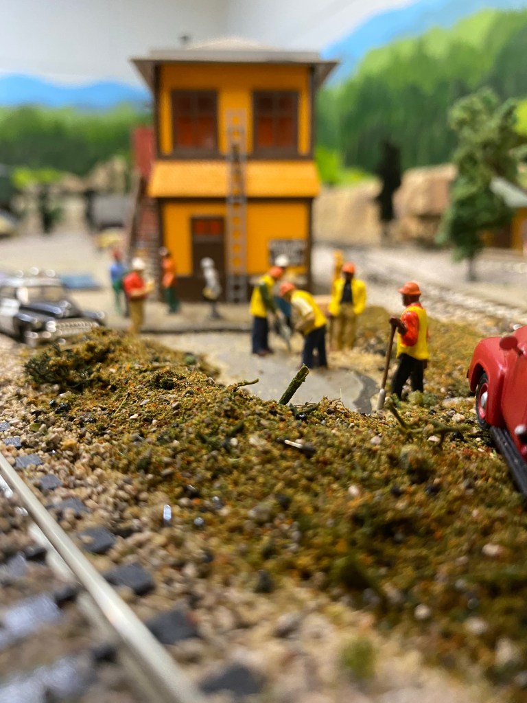 Piles of dirt surround men digging at location of watermain break.