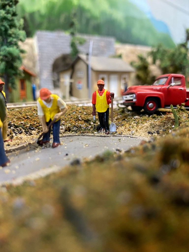 One man digs, another waits in front of red truck.