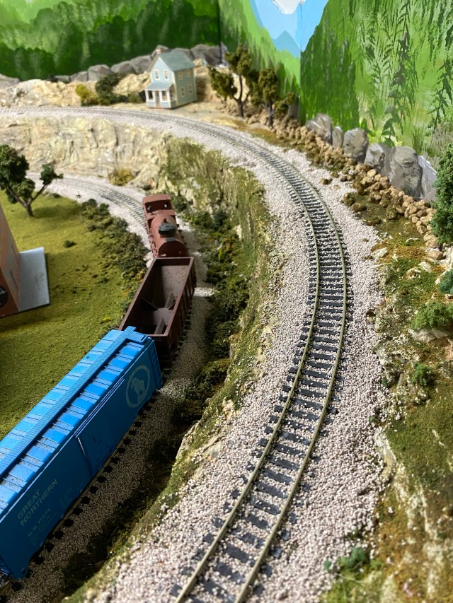 Two curved tracks, mountain ridge, rocks, backdrop, house, grass