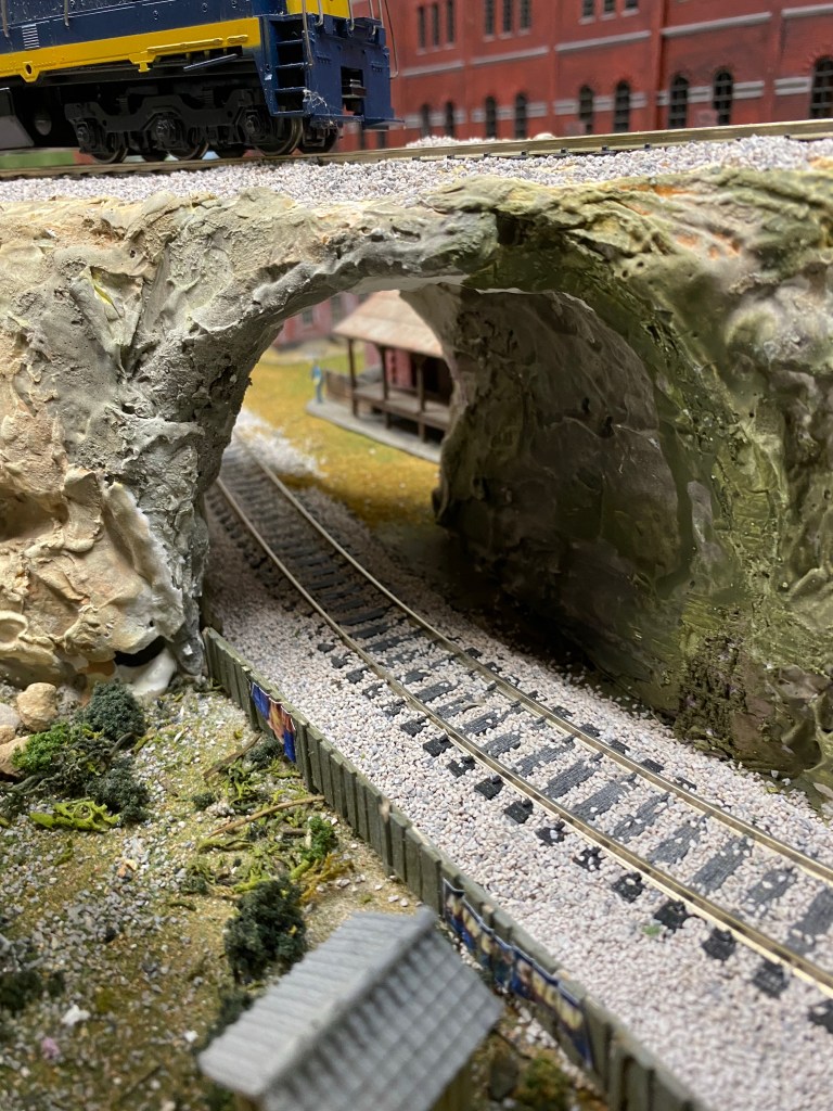 Track, shed, tunnel, locomotive, fence, dirt, rocks