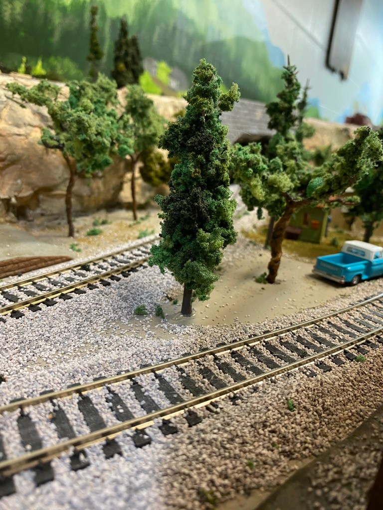 Two tracks, blue truck, trees, hills