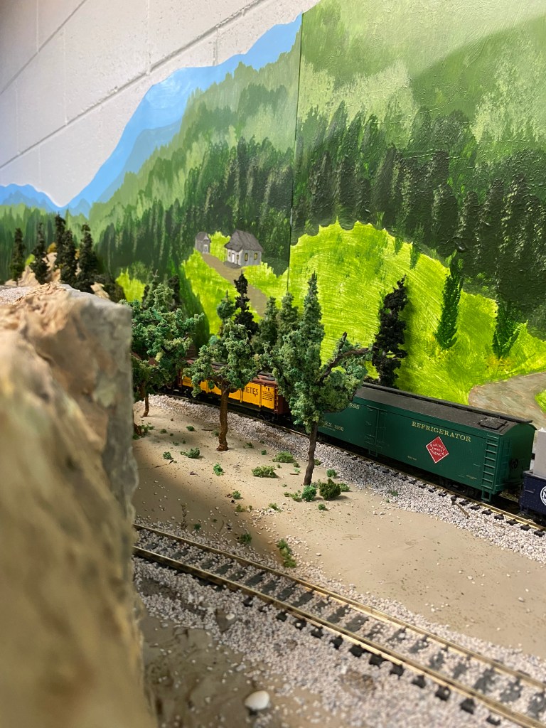 Tracks, trees, freight cars, mountain ridge