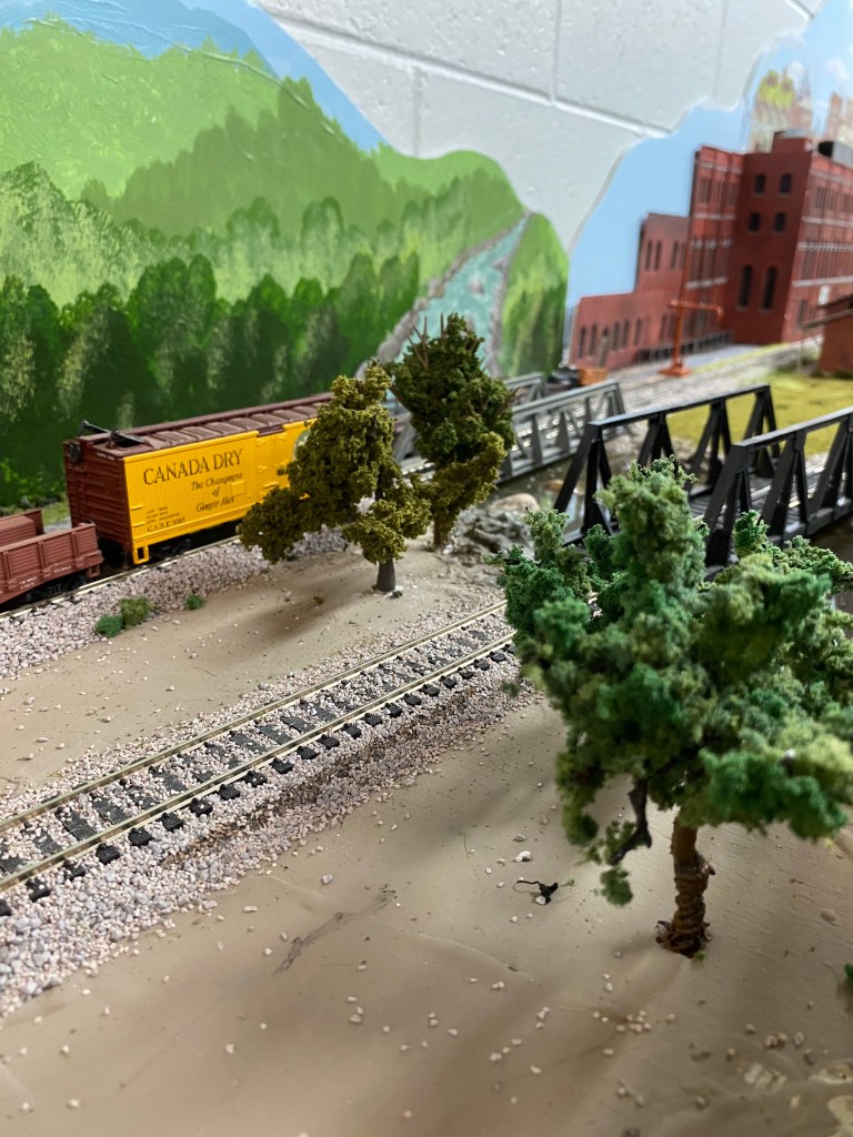 Trees, tracks, train cars, bridges, hills, building