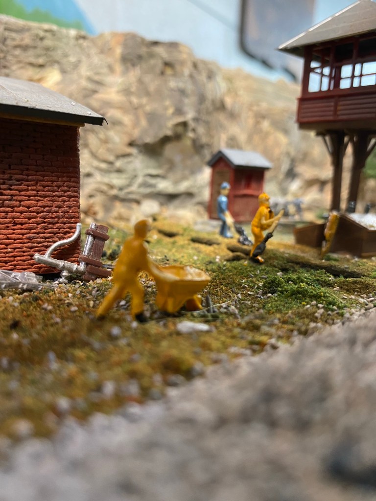 Sheds, interlocking tower, men are hard at work beside the tracks.