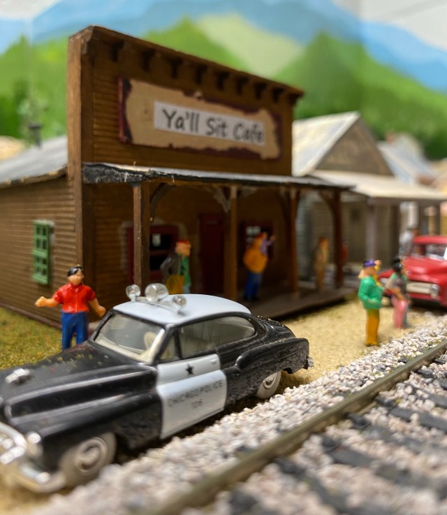 Police car, people, Ya'll Sit Cafe, red truck, train track