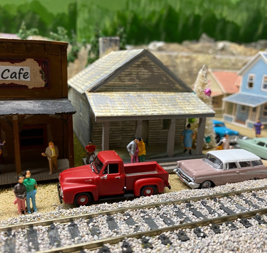 Red truck, cars, stores, track, people,