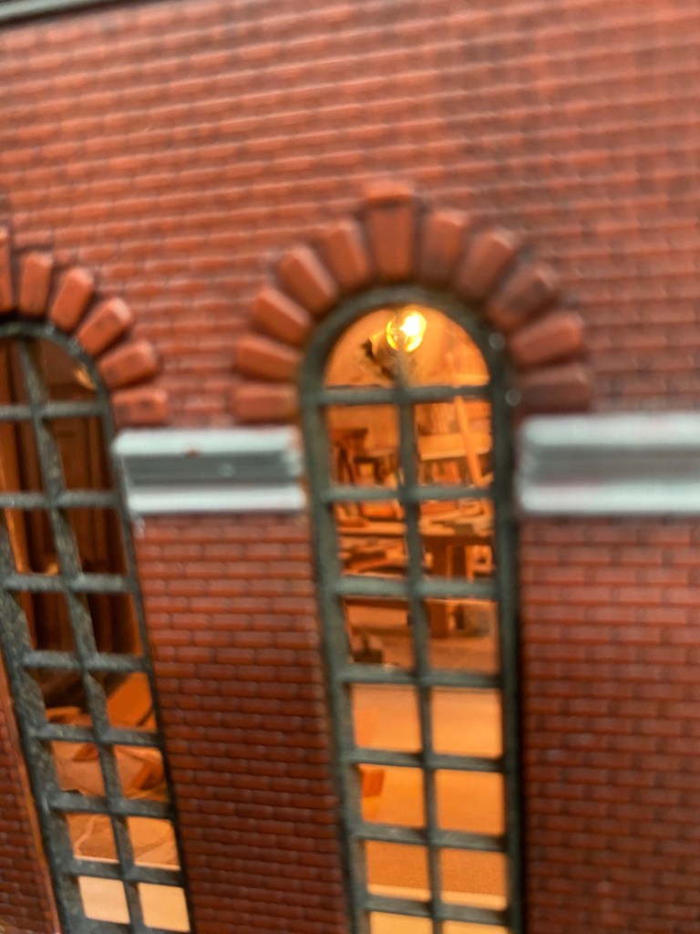 A view through the window of the Maple Valley Manufacturing plant with the work benches and tools visible.