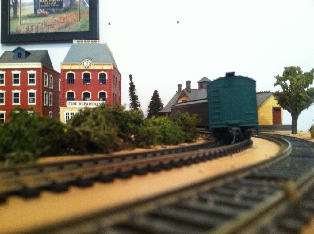 Parallel tracks, train cars, buildings, bushes