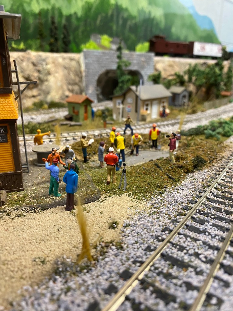 HO scale track, workers, people watching, ground cover, weeds