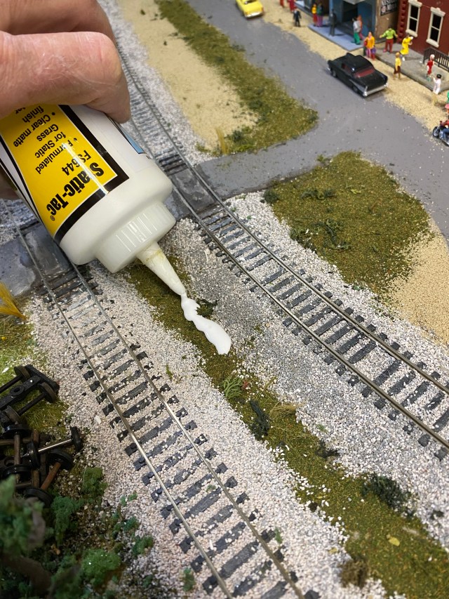 Woodland Scenics Static-Tac being poured between tracks for weeds