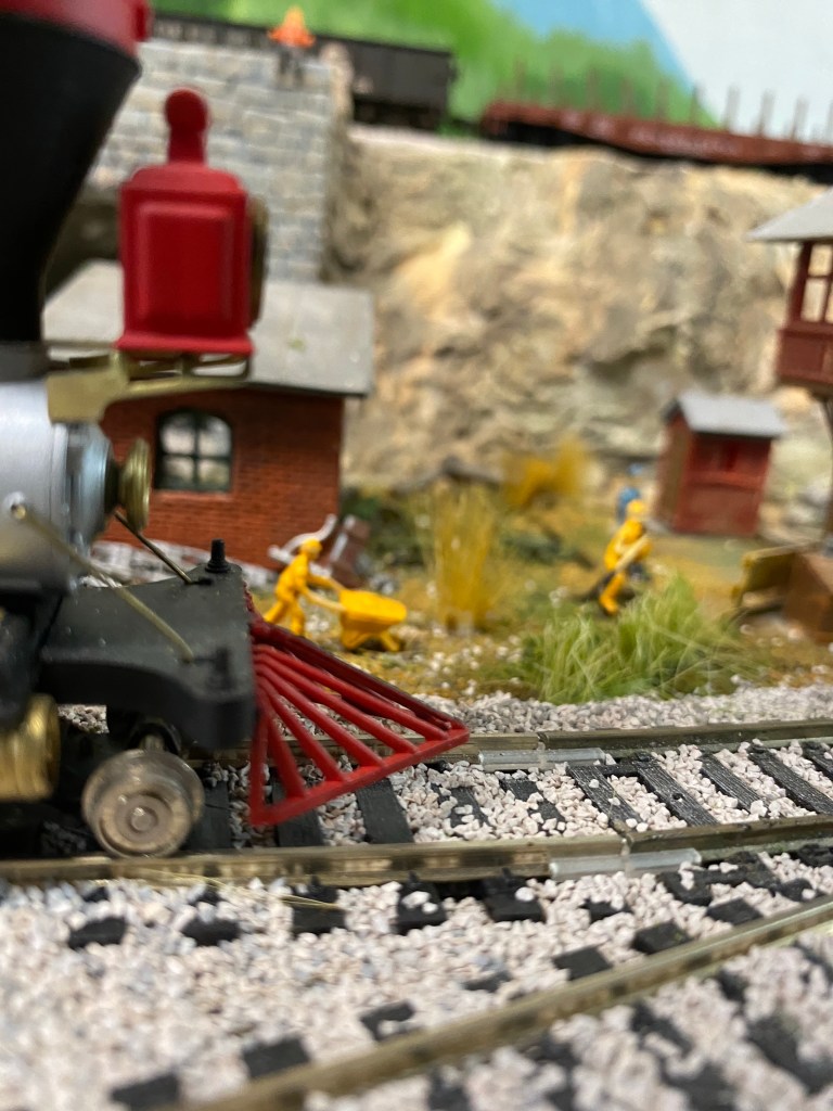 HO scale engine, track, weeds, figures, rail cars