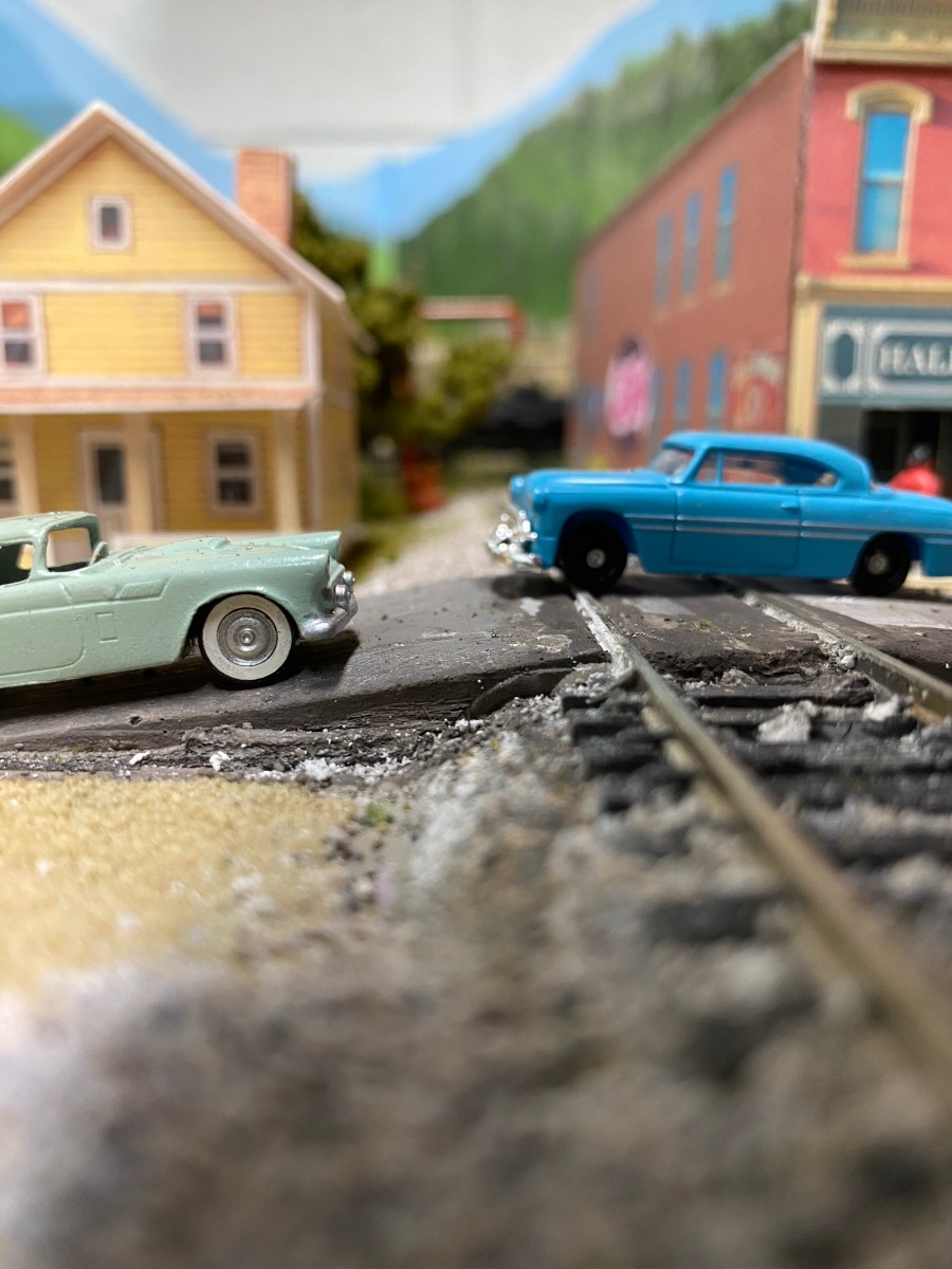 Train track, crossing two cars, buildings