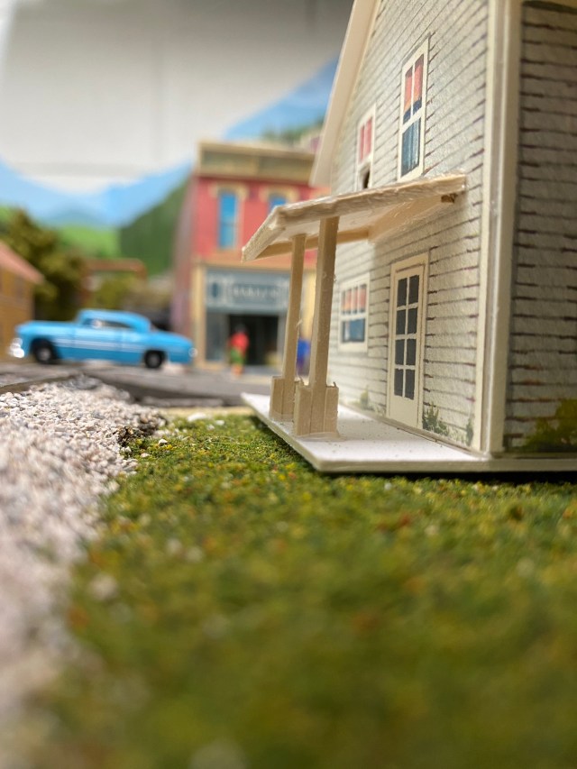 Grass, rocks, a car, the back porch of a house