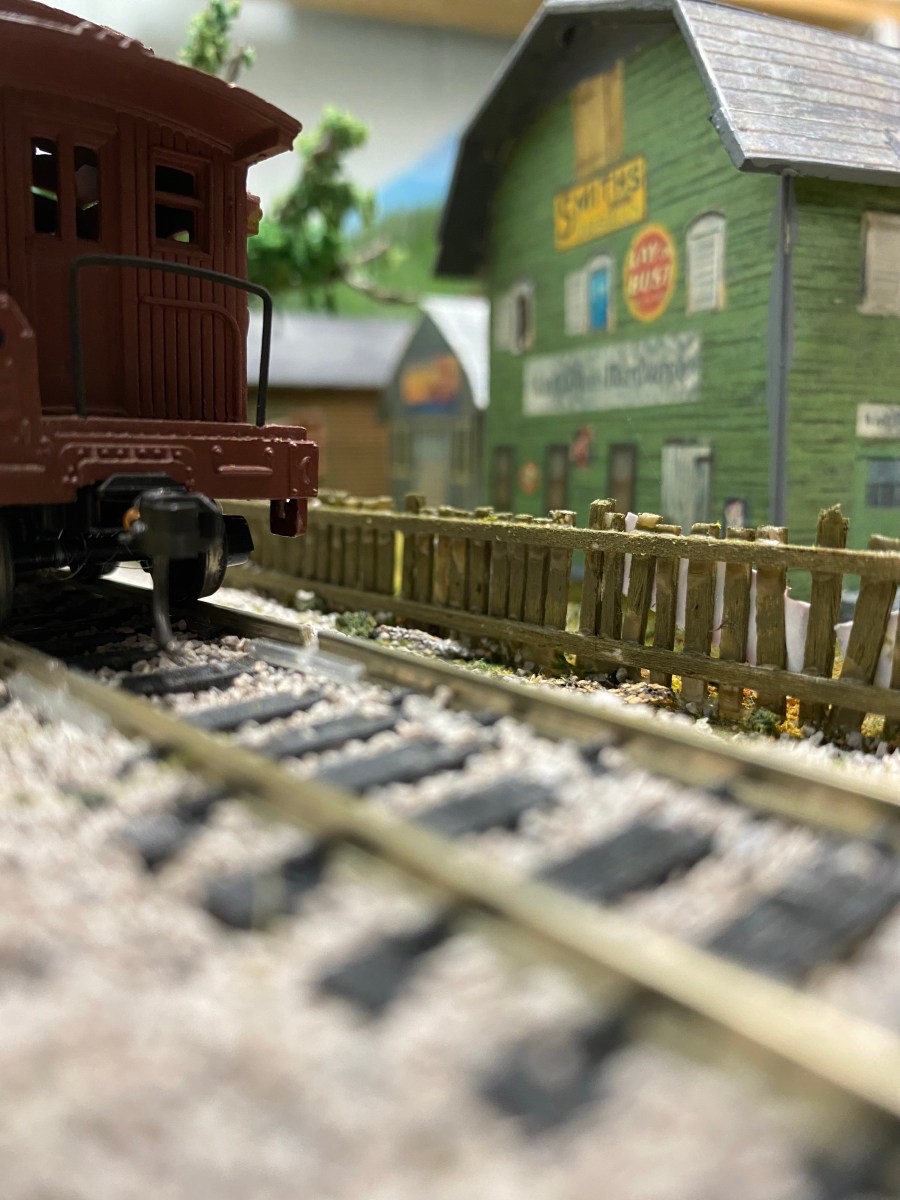 Track, a green picket fence, a building