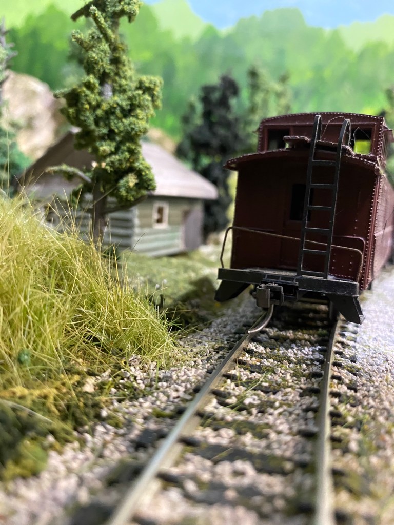 Track, caboose, weeds, trees, cabin, mountain
