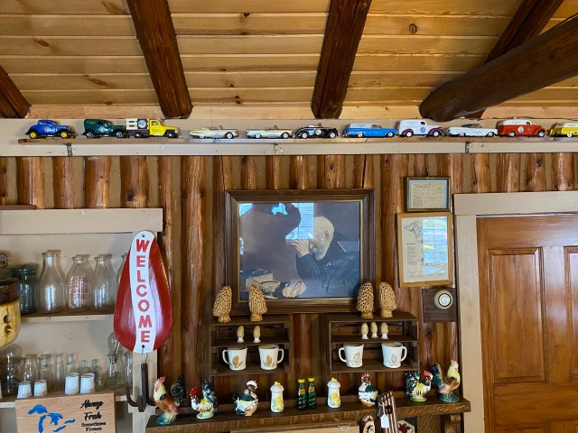 Model cars on display, photo of old man praying, antiques, mugs, milk bottles, welcome sign, door