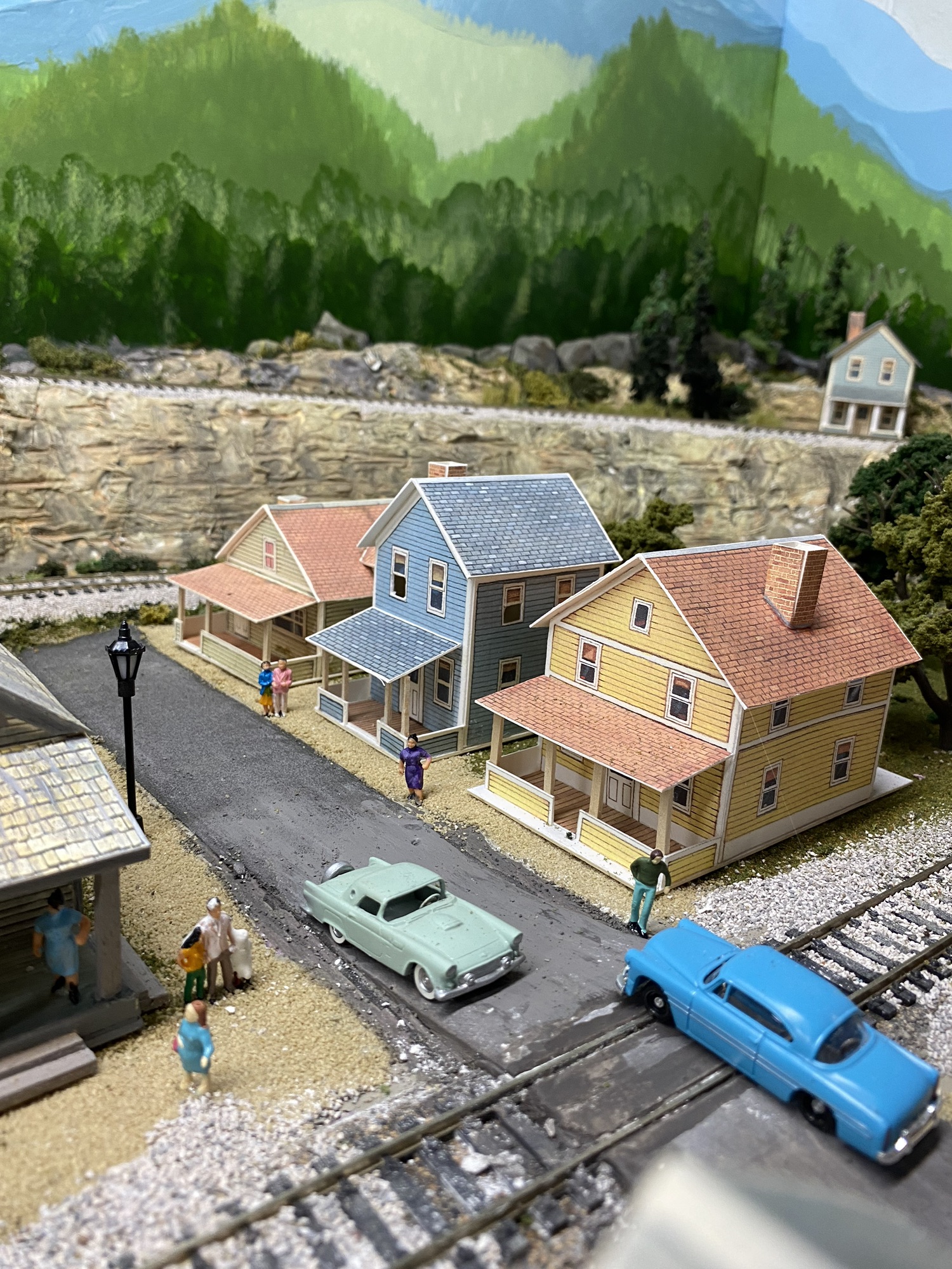 Train track, railroad crossing, cars, houses, trees