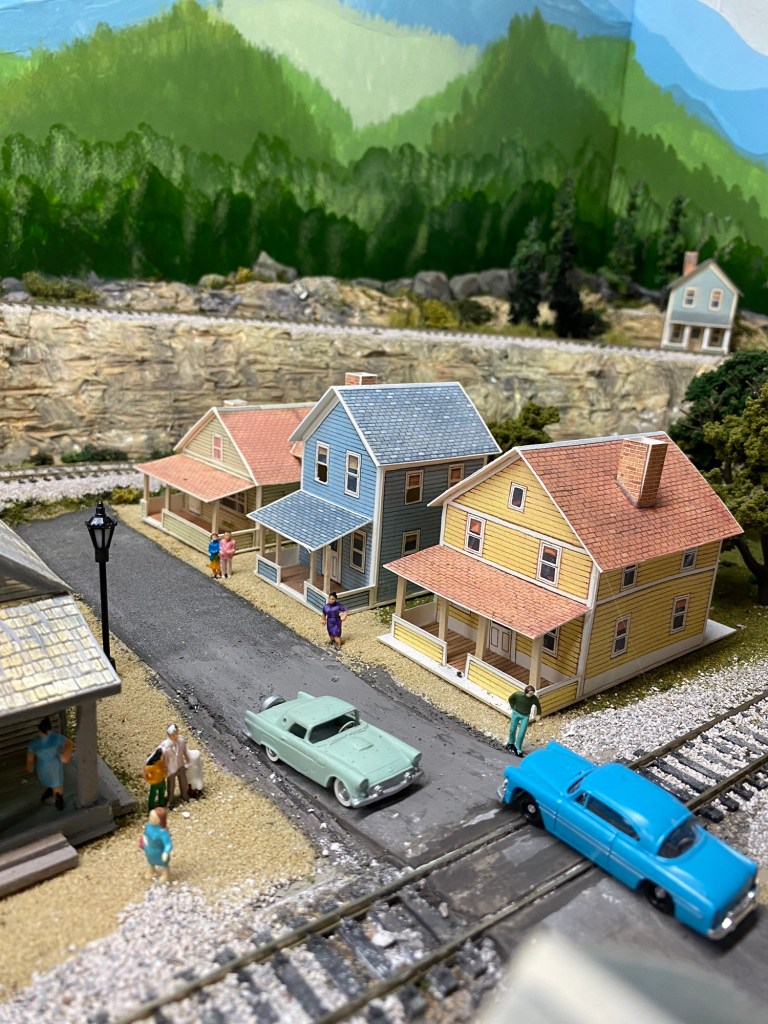 Train track, railroad crossing, cars, houses, trees