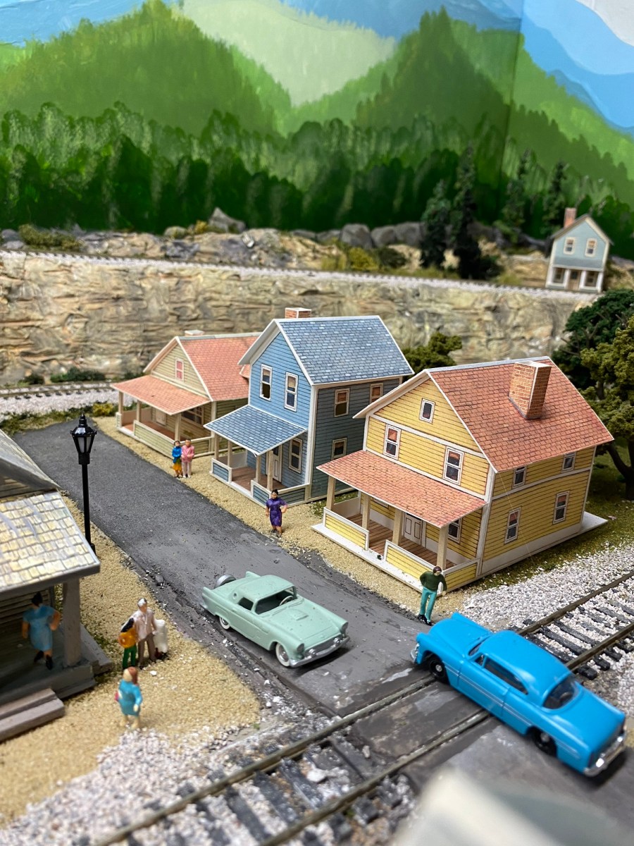 Train track, railroad crossing, cars, houses, trees