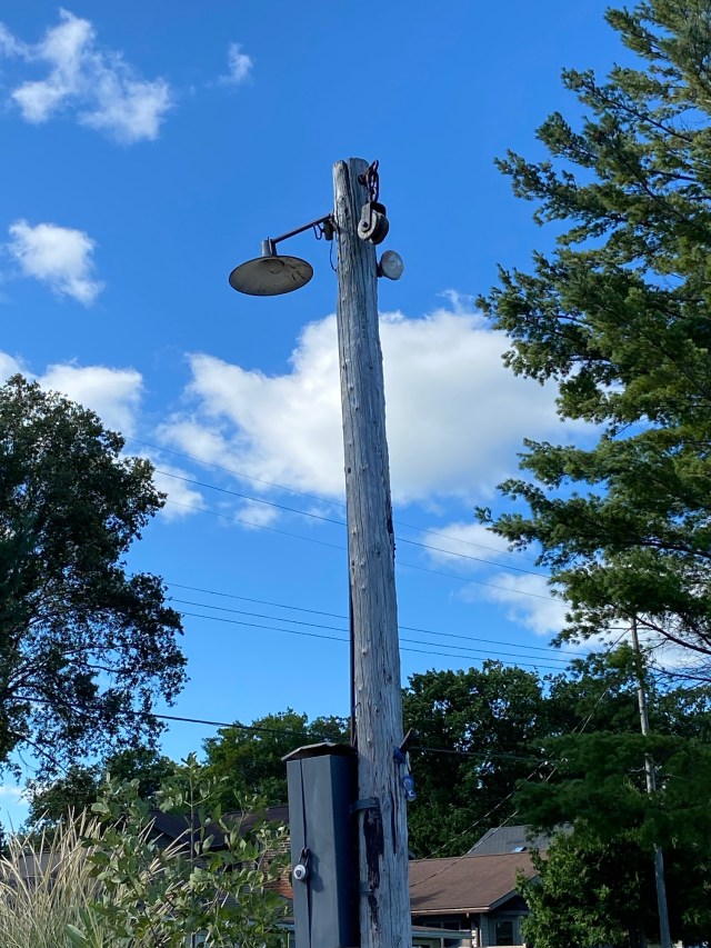 Old light pole, wooden pulley, trees, blue sky