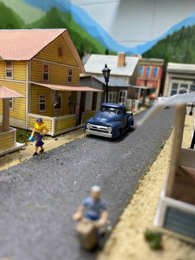 Houses, truck, child playing, woman walking, buildings, street