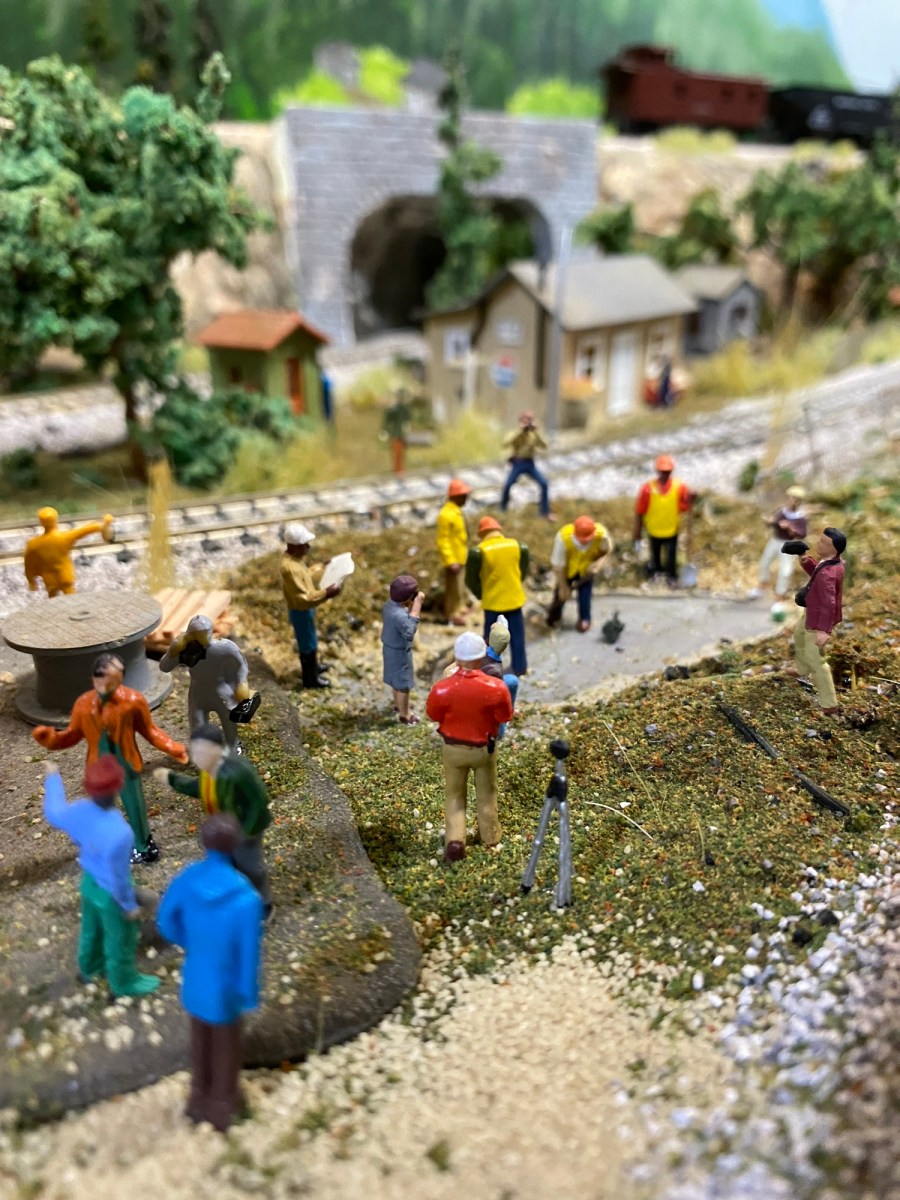 Photographers, workers, track, sheds, trees, tunnel portal