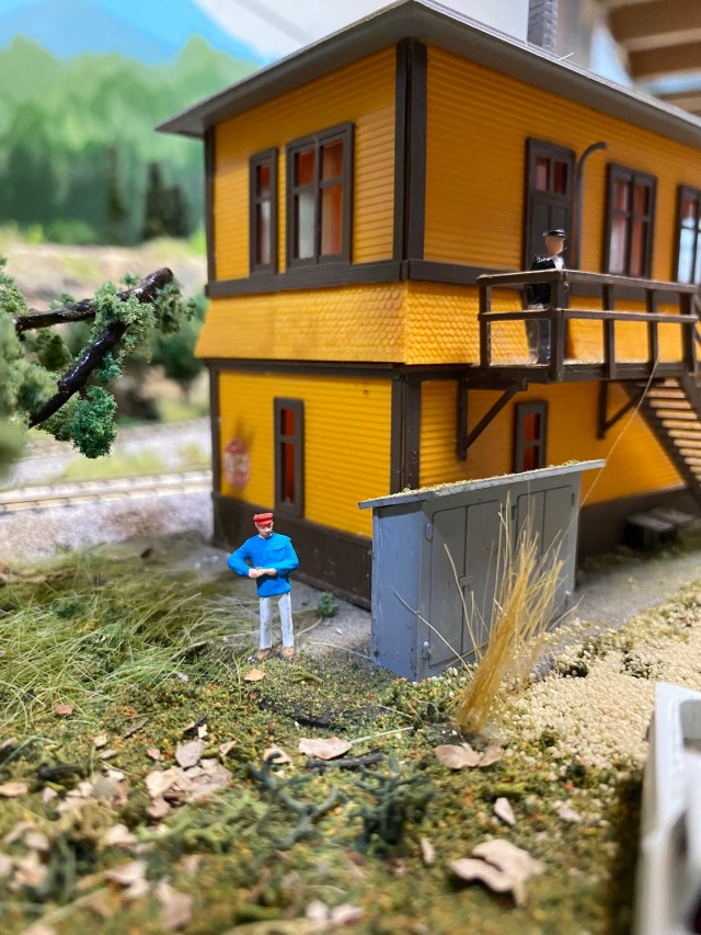 Railroad interlocking, shed, train worker, weeds, track trees