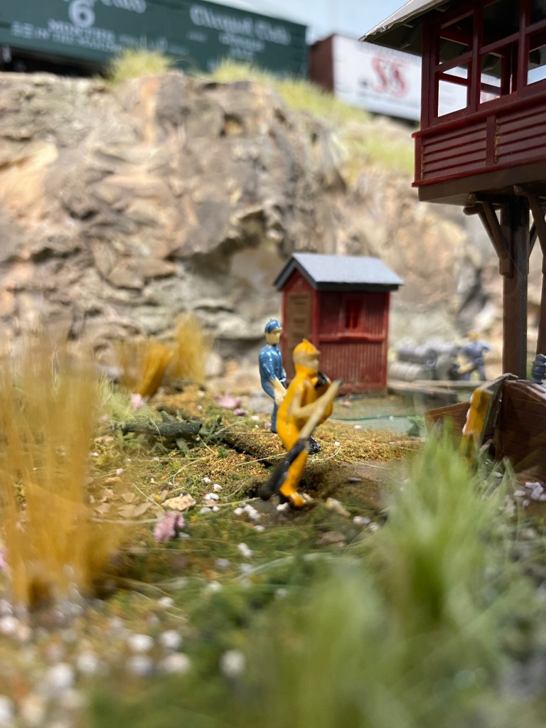 Workers, weeds, shed, tower, rocks