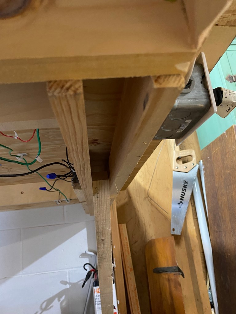 Benchwork under layout, wall bracket, girders, cement block wall, wires