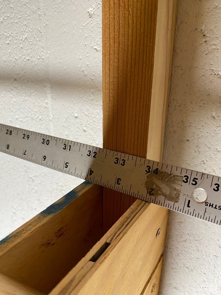 Ruler, wall bracket fastened to cement block wall.